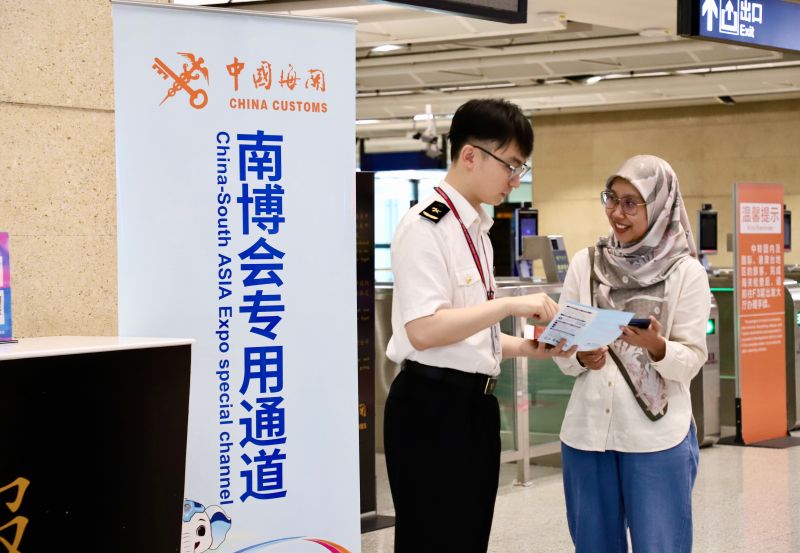 图说：海关关员在昆明机场口岸为入境旅客介绍第10届南博会相关政策（马舒娴 摄）